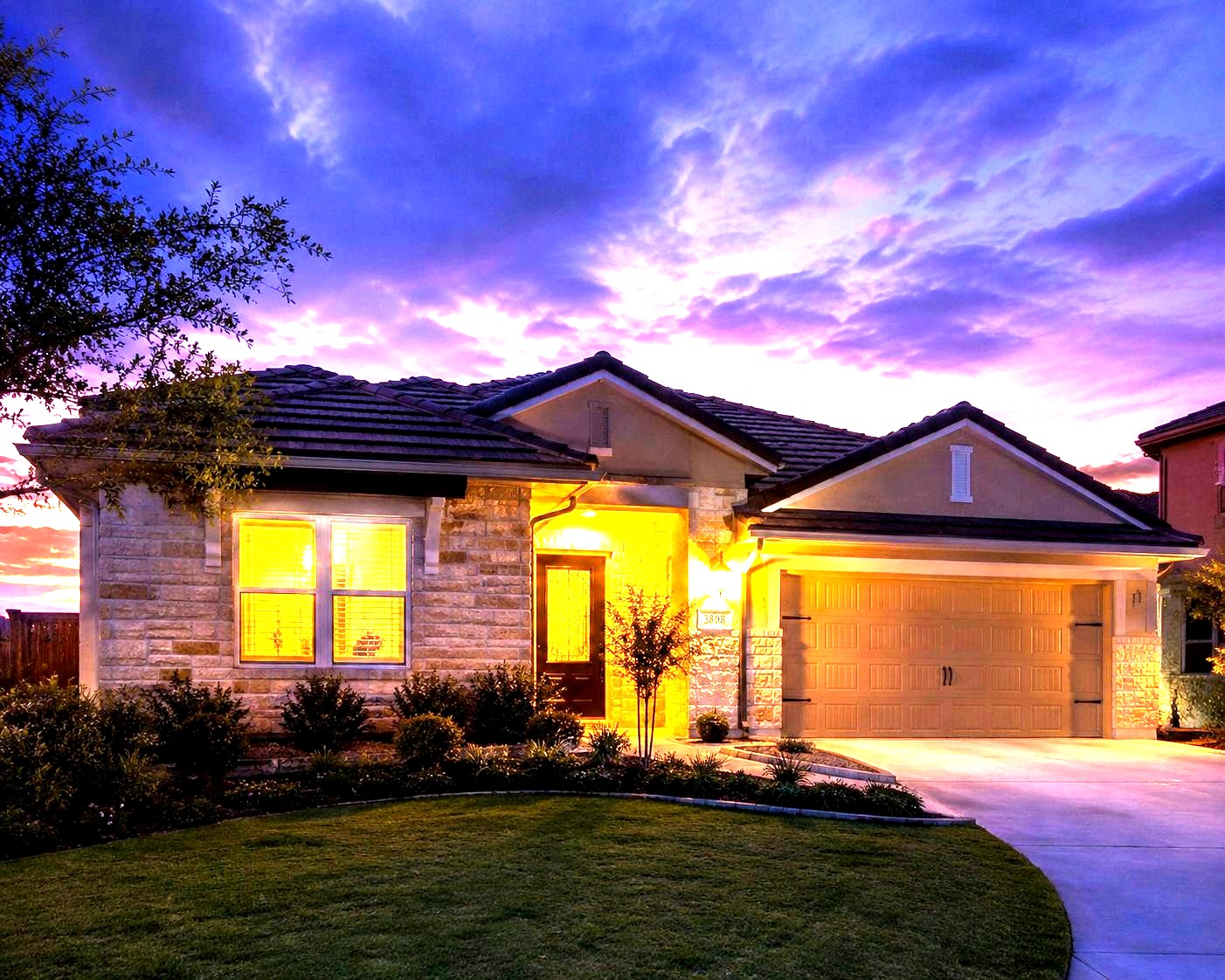 A Texas home with its lights on at dusk